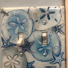 a blue and white light switch cover with sand dollar fish, starfish and shells