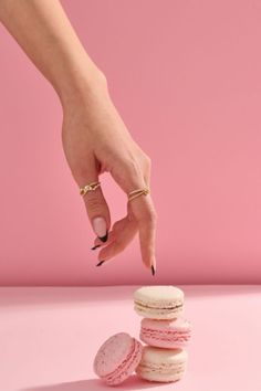 a woman's hand reaching for a stack of macaroons