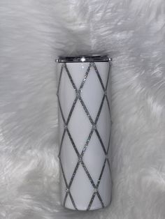 a white and silver vase sitting on top of a fur covered floor