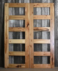 two wooden doors sitting next to each other on top of a cement floor in front of a wall