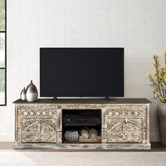 an entertainment center with a flat screen tv and vases on the floor next to it