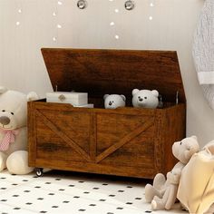 two teddy bears sitting next to a wooden box with baby's toys in it