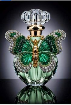 a green glass perfume bottle with a gold and crystal butterfly on it's top