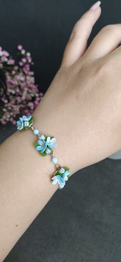 a woman's hand holding onto a bracelet with blue and white flowers on it