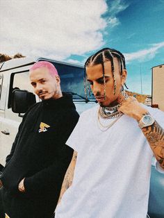 two men standing next to each other in front of a white truck with pink hair