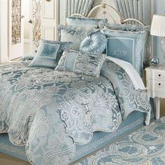 a bed with blue and white comforters in a bedroom next to a mirror on the wall