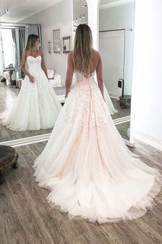 a woman in a wedding dress looking at herself in the mirror