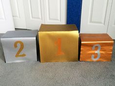 three small blocks with numbers on them sitting in front of a door, one is gold and the other is silver