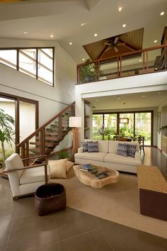 a living room filled with lots of furniture and a stair case in front of it