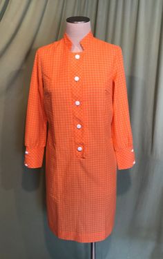 "This is a cute vintage dress from the early 60s. Label reads, \"Patti Green\". Tagged a size 14. The bust measures 38\", waist 36\", see measurements below, but it would look best on a slightly smaller bust & waist. Made of permanent press cotton blend fabric in bright orange with a white check pattern in the weave. The dress is not lined. The sleeves are long with wide button cuffs. The neckline is a small stand up collar. Buttons to below the waist with white plastic buttons. The dress is Stand Up Collar, Pleated Bodice, Cute Sets, Gathered Skirt, Fashion Fabric, Vintage 60s, Green Orange, Dress Clothes For Women, Skirt Outfits