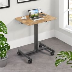 a laptop computer sitting on top of a wooden table next to a potted plant