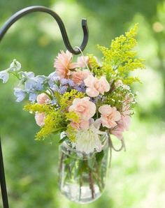 a vase filled with lots of flowers on top of a metal hook that says good morning