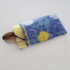 "This double pocket sleeve or case is a great organizer for 2 pairs of glasses. This case is made up in a blue, aqua, purple and yellow floral design cotton print fabric with a contrast yellow polka dot fabric. There is a purple cotton fabric lining. The main pocket will accommodate your sun glasses or eye glasses and the outside pocket is an easy slip in for your readers or a second pair of glasses. The pockets are also a designed to fit your cell phone and one pair of glasses, should you choos Blue Zipper Pouch Case For Storage, Blue Zipper Pouch Case, Blue Rectangular Case For Personal Use, Blue Rectangular Case For Everyday Use, Blue Cases With Pen Holders For Daily Use, Blue Cases With Pen Holders, Purple Cotton Fabric, Yellow Polka Dot, Dot Fabric