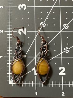 Gorgeous yellow earrings wrapped in swirly oxidized copper wire. Earrings are 2.25 inches long and .5 inches wide. Comes with nickel free french wire hooks. Handmade Brown Copper Wire Earrings, Brown Copper Wire Wrapped Earrings, Wire Wrapped Brown Copper Earrings, Copper Wire Wrapped Brown Earrings, Brown Adjustable Copper Wire Earrings, Artisan Hand Wrapped Copper Earrings, Hand Forged Brass Earrings In Brown, Hand Forged Bronze Earrings With Copper Wire, Handmade Yellow Copper Jewelry