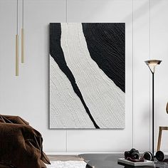 a black and white painting hanging on the wall in a living room next to a chair