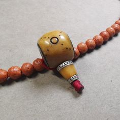 a wooden bead necklace with an orange and brown pendant on it's end