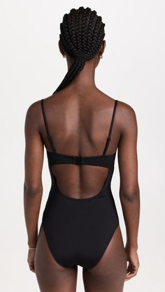 the back of a woman in a black swimsuit with braids on her hair