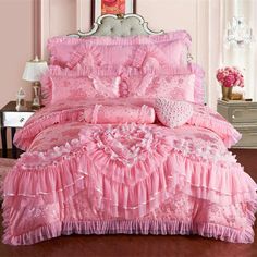 a pink bed with ruffled bedspread and pillows