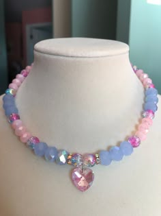 This aurora borealis pink heart charm choker stuns with pink and blue crackle glass beads, light blue aurora borealis faceted glass beads, and light pink faceted glass beads. This piece is exquisite in its ability to reflect light and color. Pink Crystal Heart Pendant Necklace, Pink Crystal Necklace With Heart Charm, Pink Crystal Necklace With Faceted Beads, Handmade Pink Heart Crystal Necklaces, Pink Crystal Beaded Necklaces For Jewelry Making, Pink Heart Charm Choker Necklace, Pink Crystal Beaded Necklace For Jewelry Making, Pink Crystal Beaded Necklace For Gift, Pink Crystal Choker Necklace As A Gift