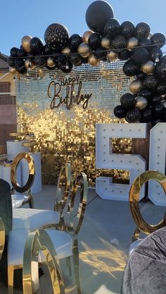 a birthday party with balloons and decorations on the table, in front of a backdrop that says happy 50th