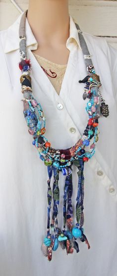 This blue tribal eclectic necklace slips on over the head and is very light, due to the fabric it is made of. It is large, at 37" around, and has 7" of beaded fabric fringe at the bottom.    The beads, that are all over this necklace, are from my collection and are made of: glass, clay, tourmaline, African stained bone, Mexican ceramics, plastic, pot metal, blue stone, and wood. I've also included a leaf charm and a grape cluster charm.    This is a statement necklace that I recently made. It has an elegant feel even though BOHO tribal in nature. I photographed it being worn on a life sized mannequin, and also next to a 12" ruler, to give a sense of size.    Please email if you have any questions about this handmade Art Necklace.    Thanks for looking! Hippie Blue Necklaces For Festivals, Blue Hippie Necklaces For Festivals, Blue Hippie Necklace For Festivals, Artisan Blue Beaded Necklaces For Festivals, Blue Beaded Necklaces For Festivals, Blue Bohemian Beaded Necklace For Festivals, Blue Hippie Beaded Necklaces, Blue Hippie Beaded Necklace, Blue Hippie Beaded Necklace With Colorful Beads