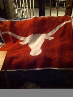 a red blanket with white longhorns on it sitting on a table next to a laptop