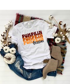 a white shirt that says pumpkin pumpkin season on it next to some cotton flowers and boots