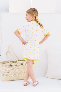 The Mini Delilah Dress will have you feeling like a dainty daisy in no time. With a playful white and yellow crocheted print, this knee-length dress features a V-neckline, contrasting trim, and functional front buttons adorned with pearls and rhinestones. Plus, the fully lined non-stretch fabric ensures both style and comfort. Yellow Daisy Print Summer Dress, Spring Cotton Crochet Dress With V-neck, Spring Mini Dress With Crochet Trim, Spring V-neck Dress With Crochet Trim, Playful White Spring Dresses, White Crochet Trim Dress For Vacation, White Fitted Crochet Dress In Cute Style, Spring Dresses With Crochet Trim And Short Sleeves, Yellow Short Sleeve Dress With Lace Trim