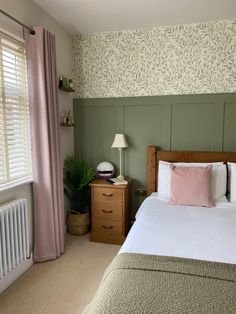 a bedroom with green walls and white bedding, pink pillows and two nightstands