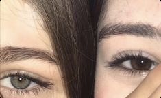 two people with brown eyes are looking at the camera and touching their foreheads together