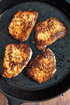 four pieces of meat cooking in a skillet