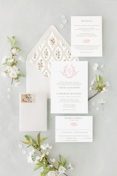 the wedding stationery is laid out on top of each other, with white flowers and greenery