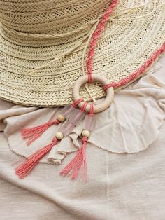 a straw hat with tassels and beads on it sitting on top of a white cloth