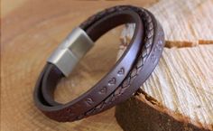 Handmade Leather Bracelet with Engraved Text in the Leather. The Leather bands on this Men's Bracelet can be personalized with a text, we will engrave your text in the leather with our laser engraving machine. The clasp of this bracelet can be engraved with a text and/or image of your choosing. In the photo's of this listed item you can see which images we can engrave on the clasp for you. If you don't see an image you like, but would still like to have an image engraved, you can always reach ou Everyday Engraved Brown Bracelets, Everyday Brown Engraved Bracelets, Personalized Leather Bracelets For Anniversary, Stamped Leather Bracelet As Gift, Personalized Brown Leather Bracelets, Handmade Leather Friendship Bracelets, Leather Bracelet Jewelry For Gifts, Brown Hand Stamped Bracelets For Everyday, Heart-shaped Leather Jewelry For Gifts