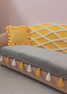 a couch with some tassels on it and a pillow in the back ground