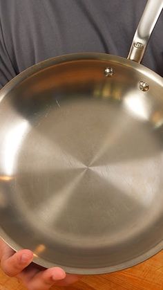 a person holding a large metal pan on a wooden table