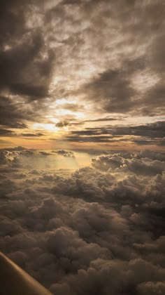 the view from an airplane looking down on clouds and sun shining in the sky above