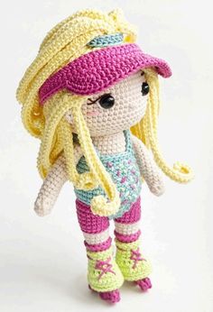 a crocheted doll is wearing a pink hat and green pants with yellow boots