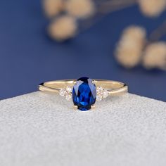 a blue sapphire and diamond ring sitting on top of a white surface