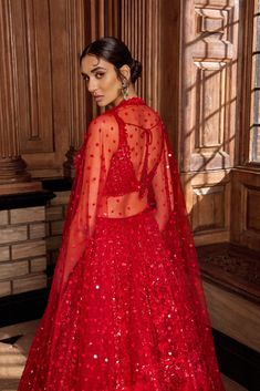 This red lehenga set features all over tonal sequin embroidery in a floral pattern. The ensemble is paired with a strappy blouse with tassels at the waist and a matching net dupatta.From Seema Gujral's A Royal Affair collection. DELIVERY TIMEPlease allow 8-12 weeks for your outfit to arrive. FABRIC DETAILSNet Professional cleaning only. Red Semi-stitched Lehenga For Evening, Glamorous Festive Net Lehenga, Festive Glamorous Net Lehenga, Glamorous Festive Lehenga In Net, Red Party Wear Choli With Mirror Work, Red Sequined Dupatta For Reception, Glamorous Net Lehenga For Festive Season, Glamorous Net Lehenga For Festive Occasions, Red Choli With Mirror Work For Party Wear