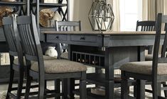 a dining room table with chairs and a bookcase in the back drop off section