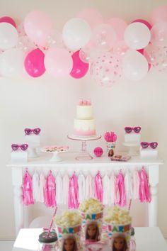 a table topped with lots of pink and white balloons