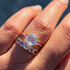 a woman's hand with a ring on it and an aquamarine colored diamond in the middle