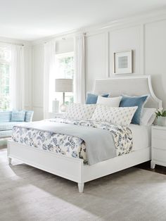 a white bed with blue and white comforters in a bedroom