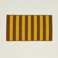 a yellow and brown striped towel hanging on a wall in front of a white wall