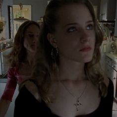 two women standing in a kitchen one is wearing a black top and the other has a cross necklace