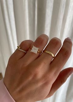 a woman's hand with two gold rings on it and one diamond in the middle