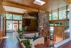 the inside of a house with stone and wood walls, plants in planters on either side of the stairs