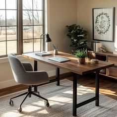 a desk with a laptop on it in front of a window and a potted plant