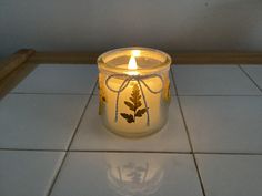 a lit candle sitting on top of a white tile floor